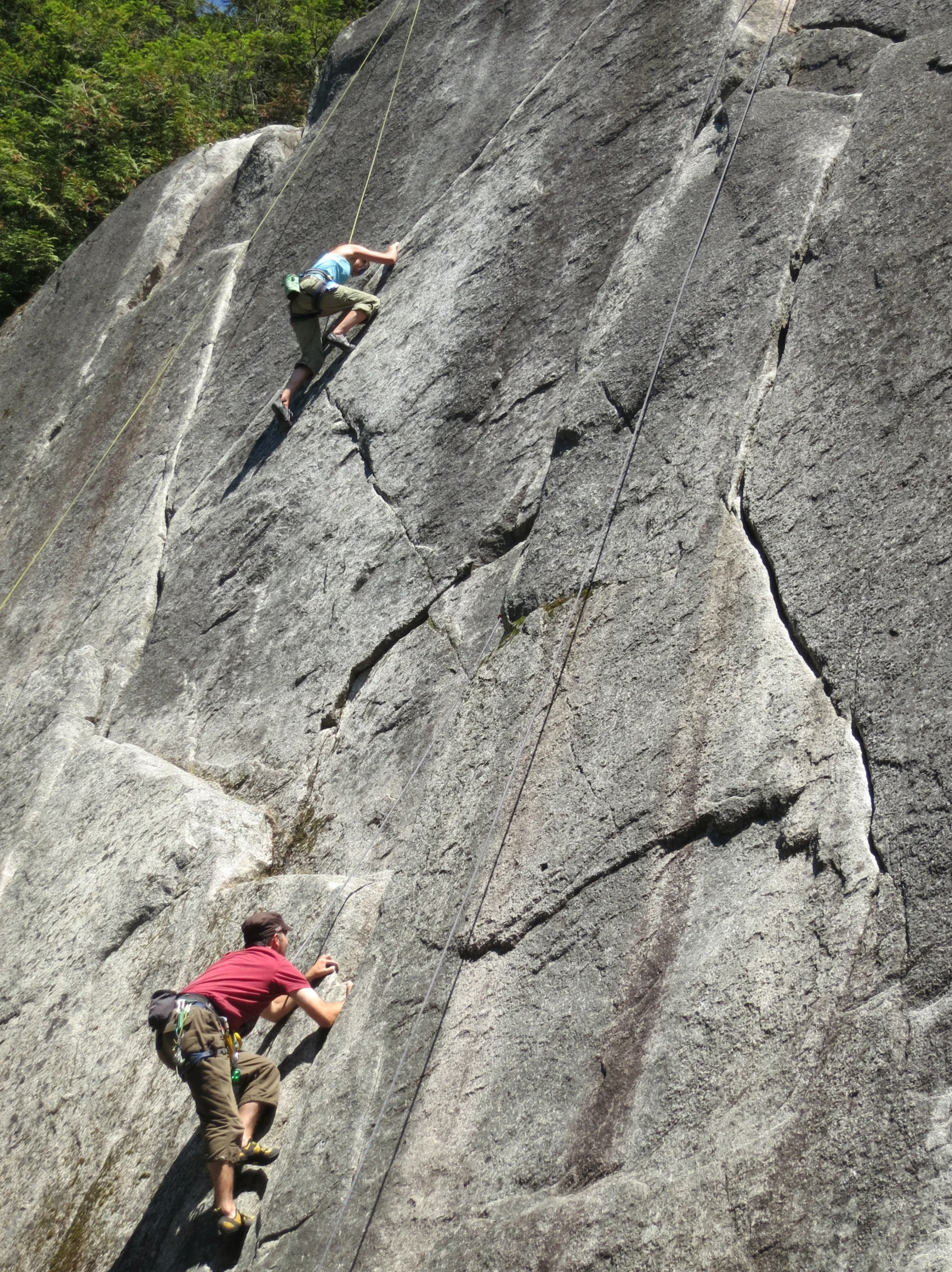 three climbers climbing the side of a rocky mountain