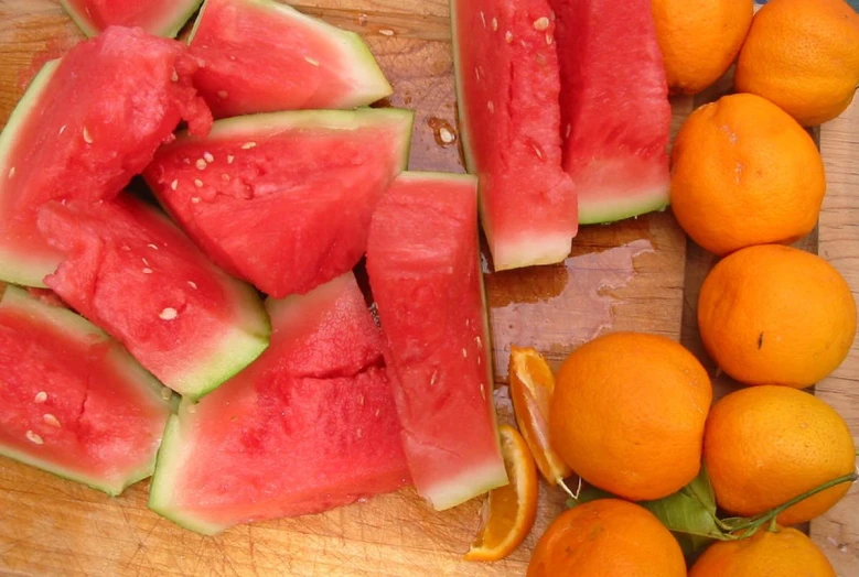 pieces of melon and oranges sit on a  board