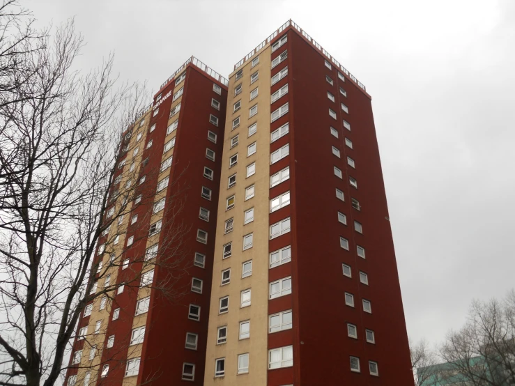 a very tall red and beige building by some bare trees