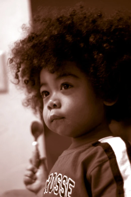 a little girl with curly hair is standing and looking to her left