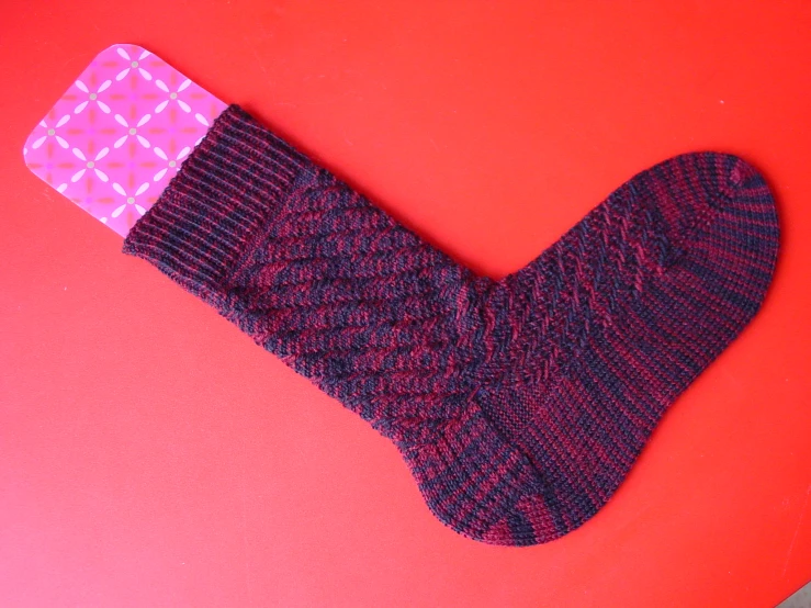a sock with a pink top laying next to some scissors