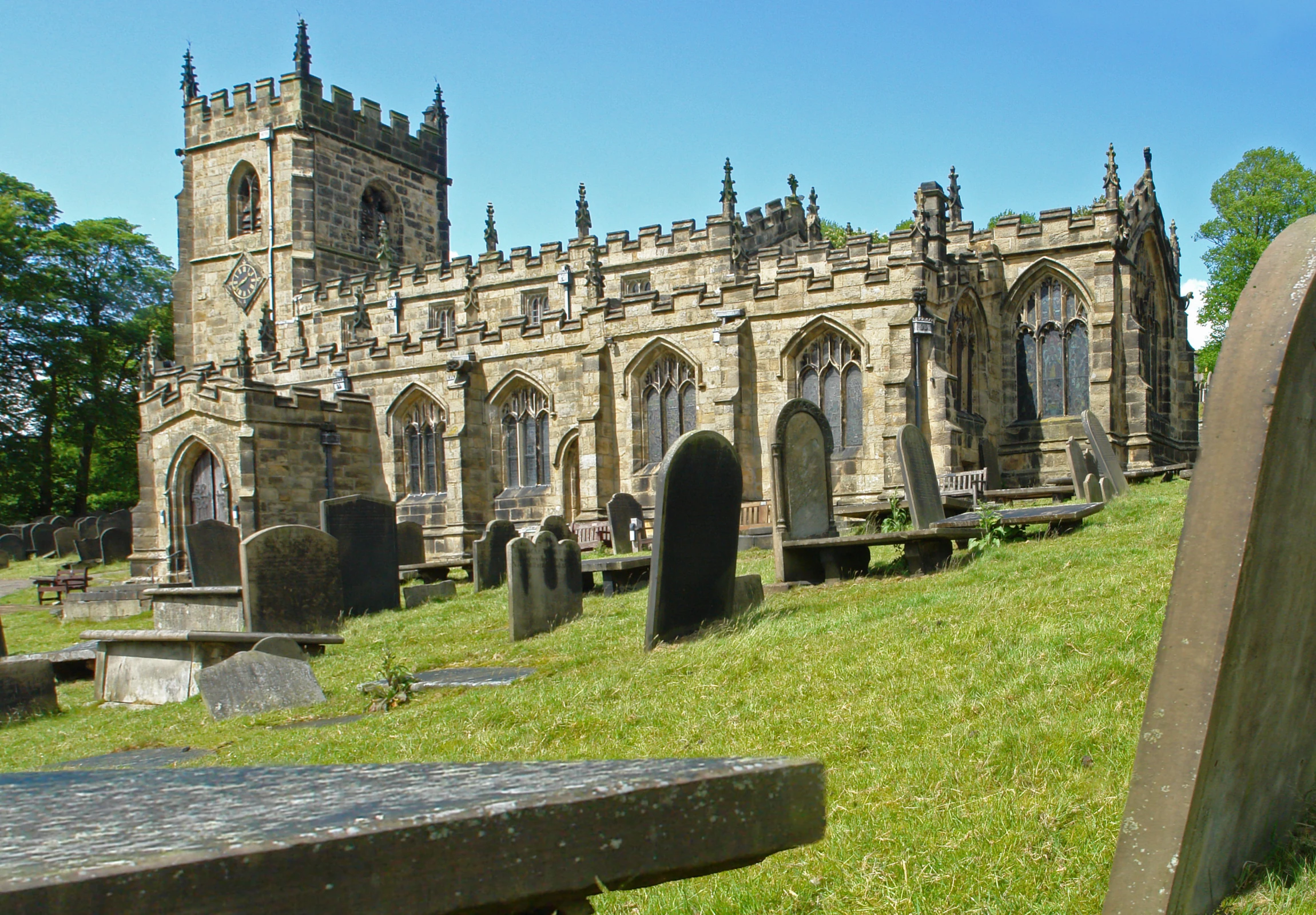 many headstones line the lawn in front of a tall, gothic era building