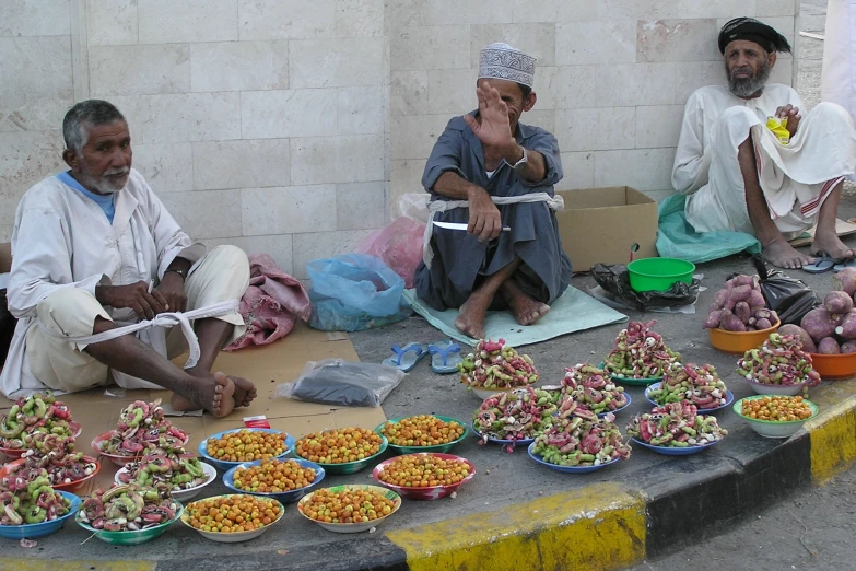 men sit outside with bowls and food