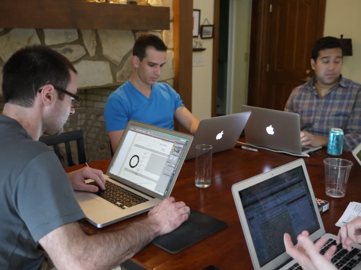 men sitting at a table with laptop computers in front of them