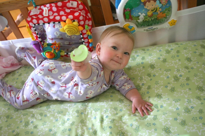 a baby playing with toy items on top of a bed