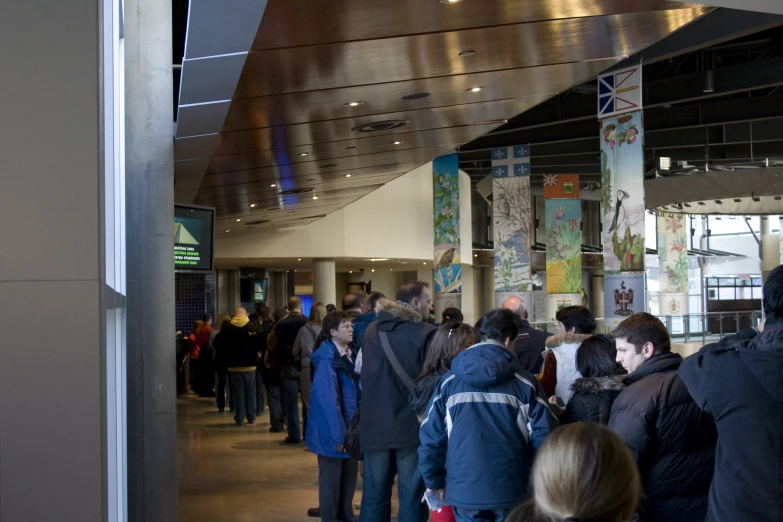 a group of people stand in a long line to get on a train