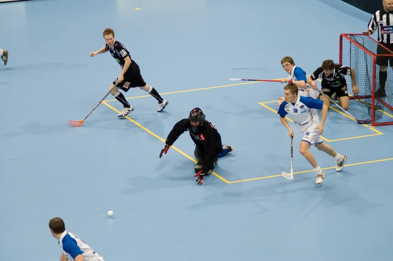 four boys are playing a game of field hockey on the court