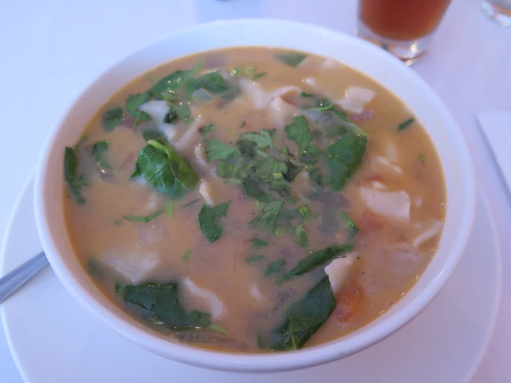 soup sitting on a white plate next to a drink