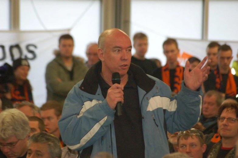 a man holding a microphone up while standing in front of a crowd