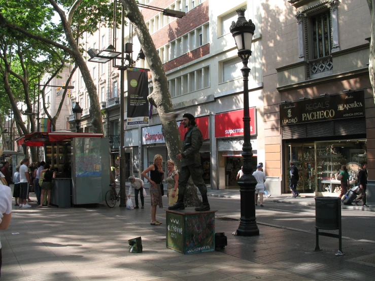 people walking on a sidewalk near buildings and a street lamp