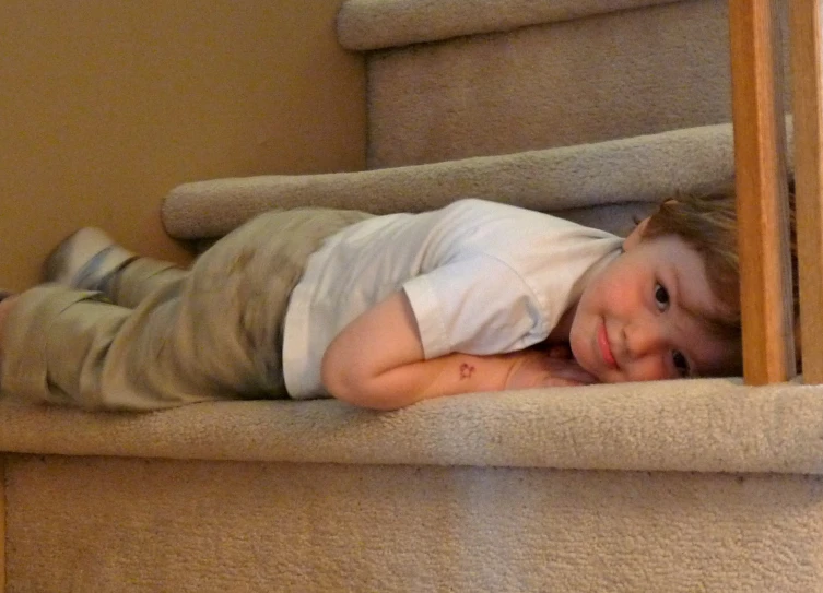 a little boy laying on the stairs looking forward
