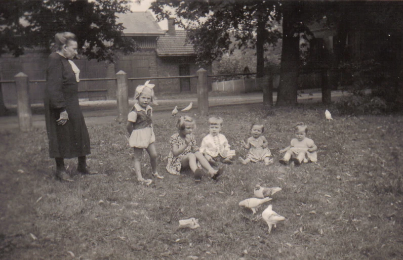 many young children sitting in the grass in front of a gravestone