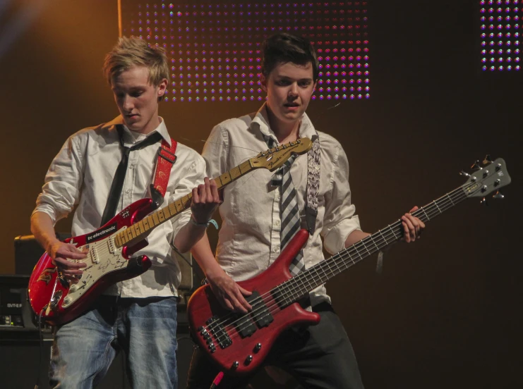 two young men playing bass guitars at the concert
