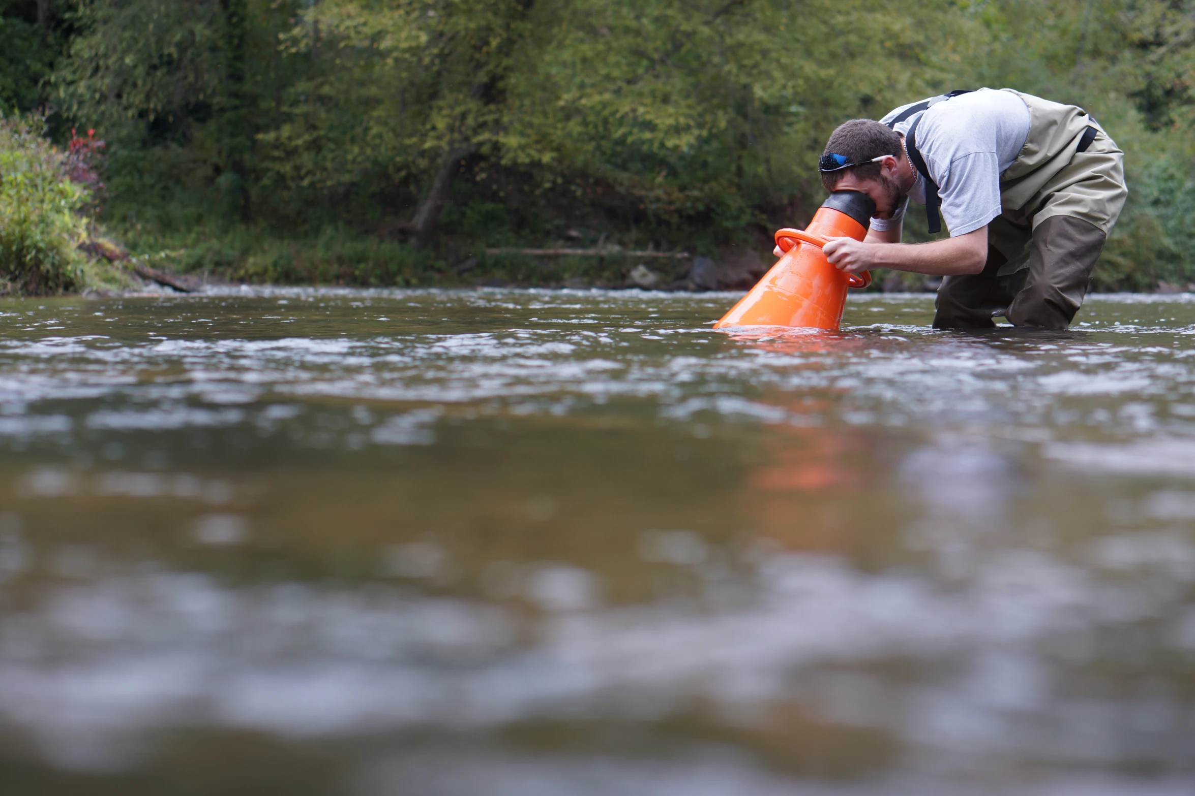 the man is using a small orange device in the water