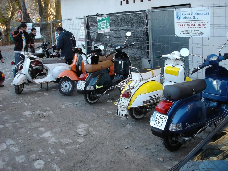several mopeds parked in front of a building and a wall
