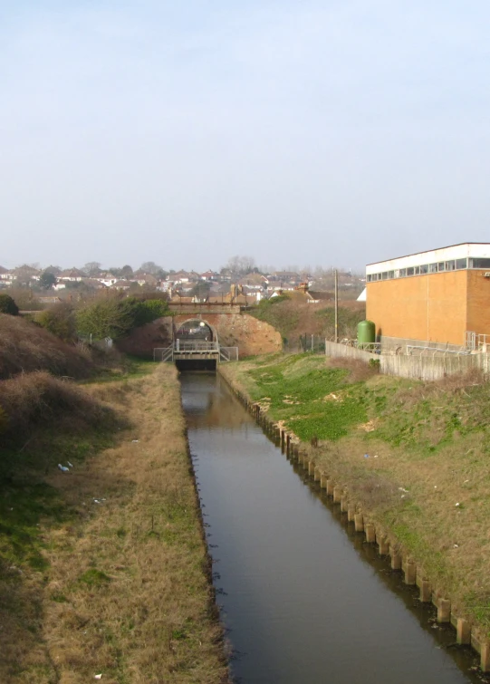 water flows between buildings in front of the green grass