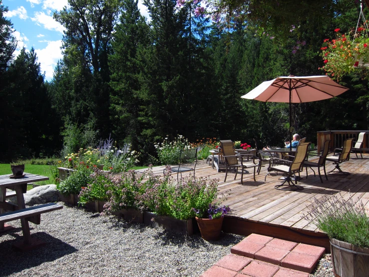 an outdoor patio is made with flagstone paving, benches and umbrella