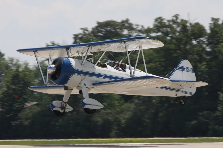 a small aircraft in mid air with trees in the background