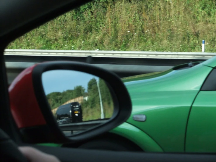 a reflection in a side view mirror on the back of a green car