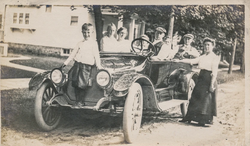 a group of men standing around an old car