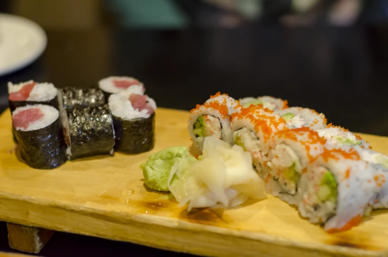 a piece of sushi sitting on top of a wooden plate