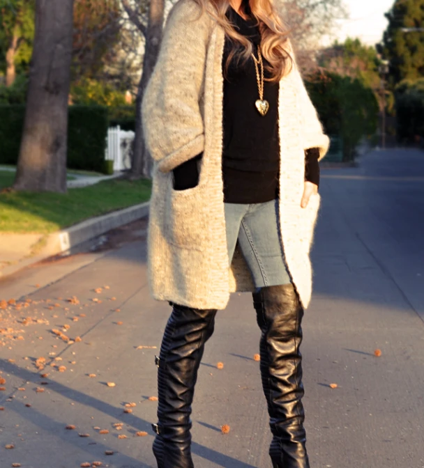 a woman wearing boots and a fuzzy coat is standing on the sidewalk
