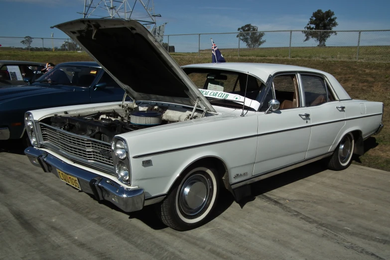 an old car has a hood open as a man stands nearby