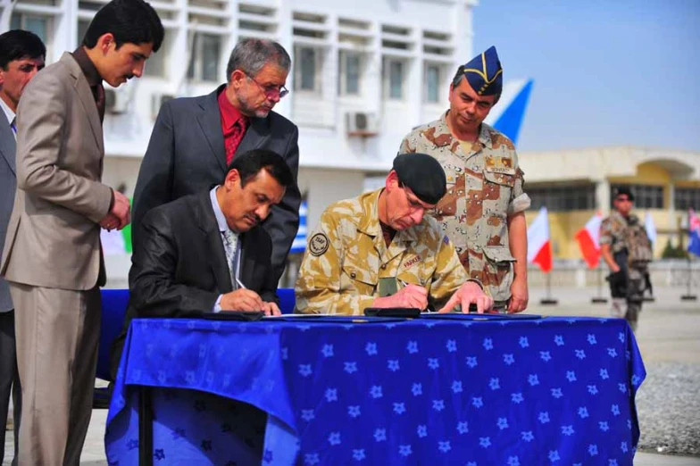 some men standing around a table signing papers