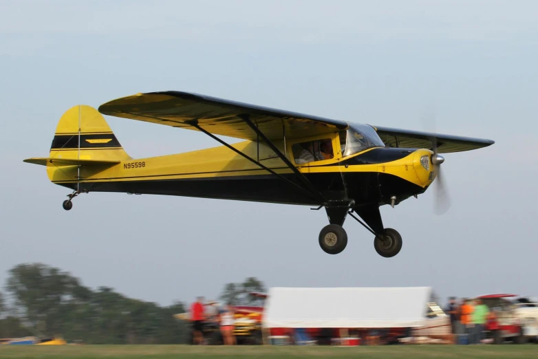 a small yellow and black airplane takes off from an airport runway