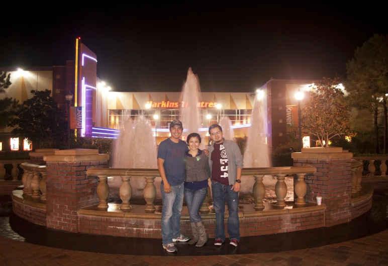 a couple of people are posing in front of a fountain