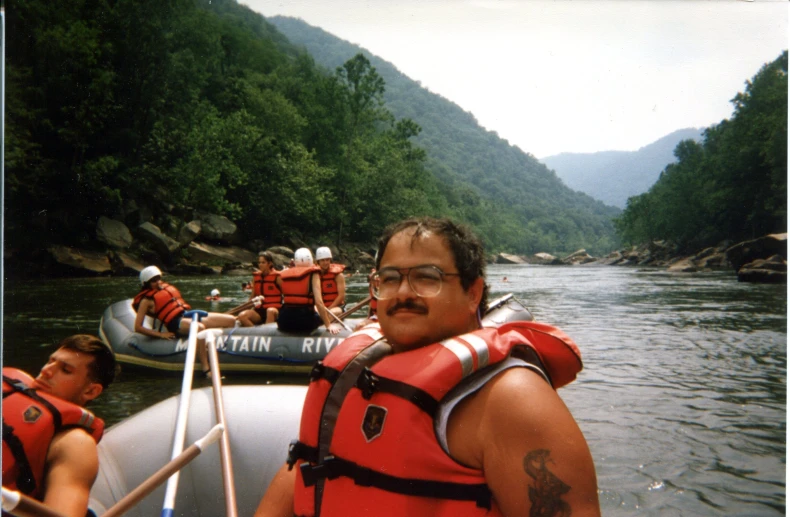 man in life vest in boat with men on raft