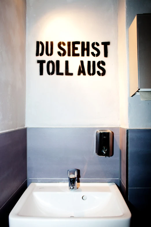 a white sink in a grey tiled room