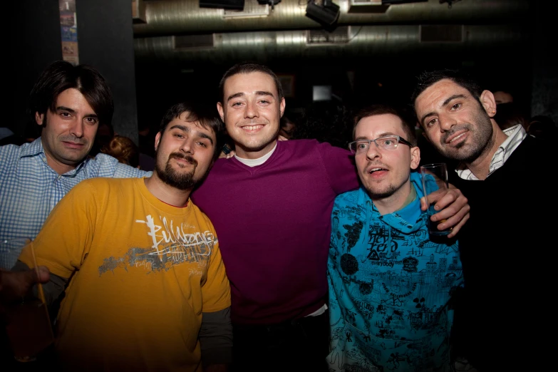 four men standing next to each other at a party