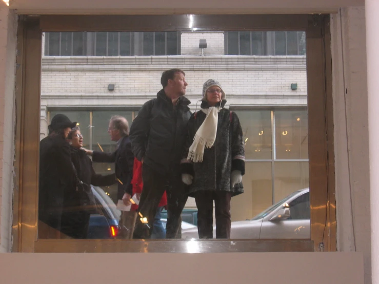 two people standing by some windows and holding soing