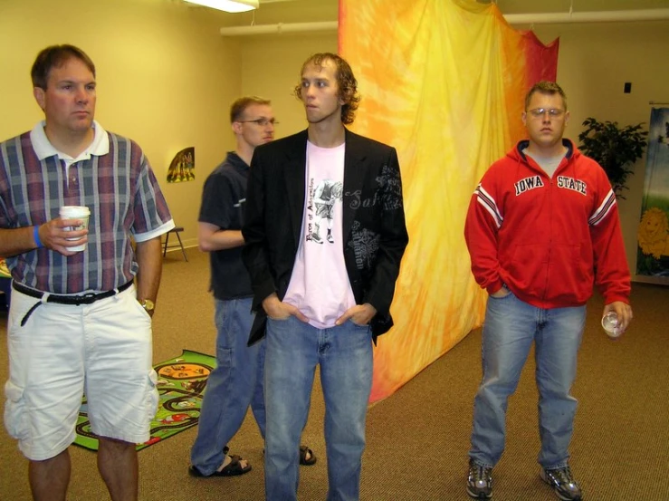 three men standing together looking at soing