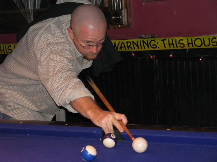 an older man is playing pool and aiming his cue