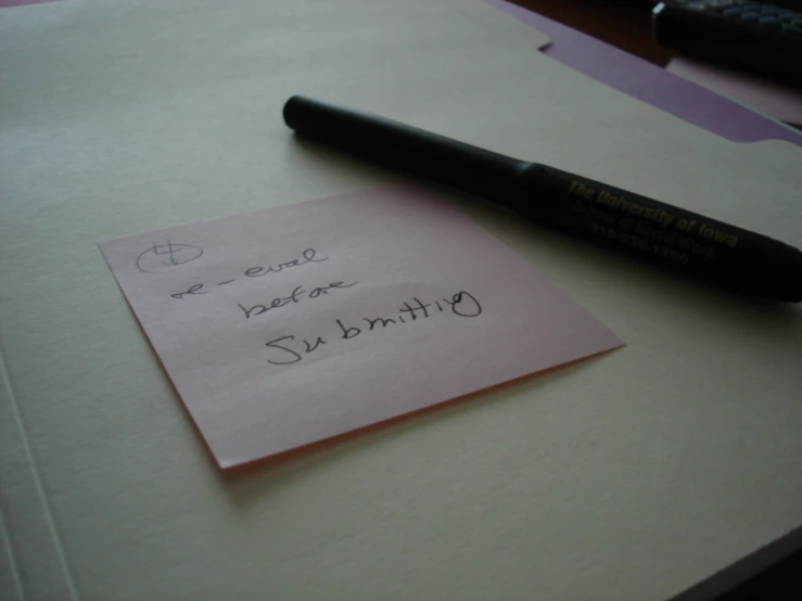 a pen, piece of paper and a stick of writing sit on a table