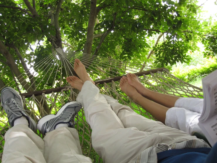 two people resting in a hammock at the park