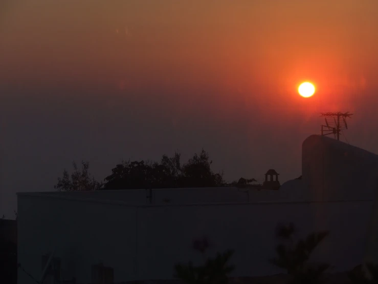 the sun is setting behind a smokey red sky