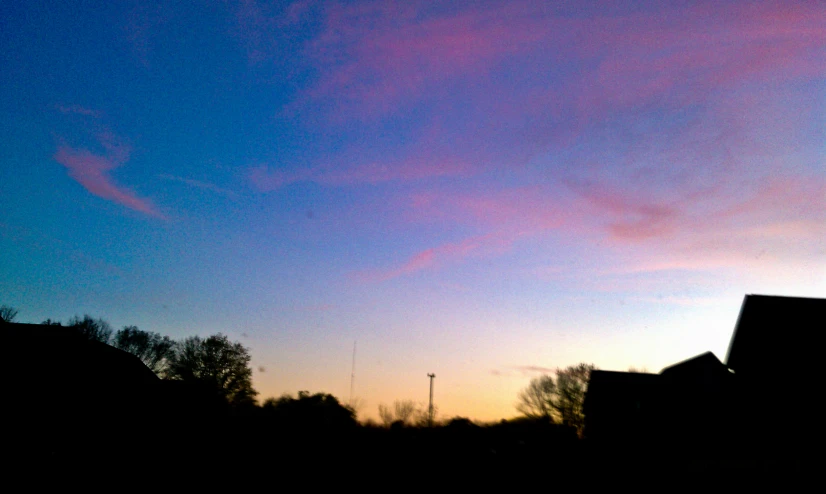 a building silhouetted against a bright pink and blue sky