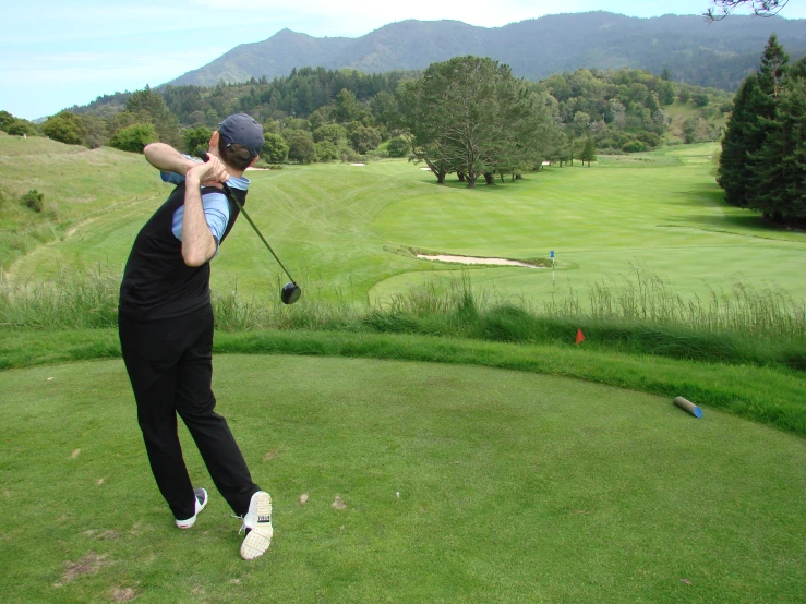 a man wearing black swinging a golf club
