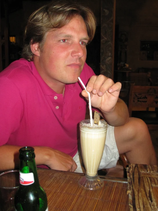 the man drinks from a milkshake with a straw