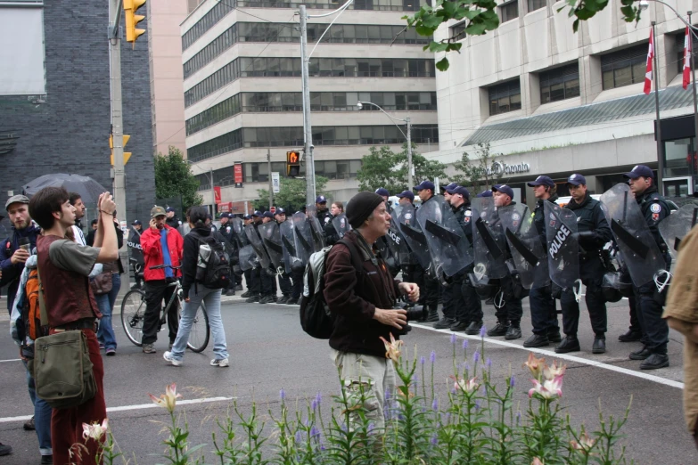 police officers are standing in the street as a group of people are marching down a city street