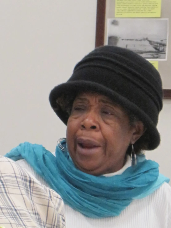 a woman wearing a black hat and scarf and a large scarf around her neck