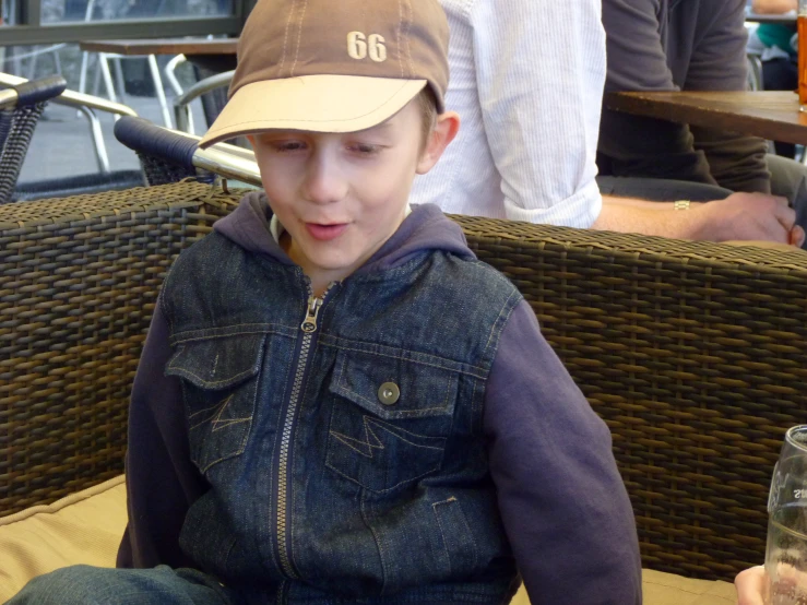 a little boy sitting at a table with a beer