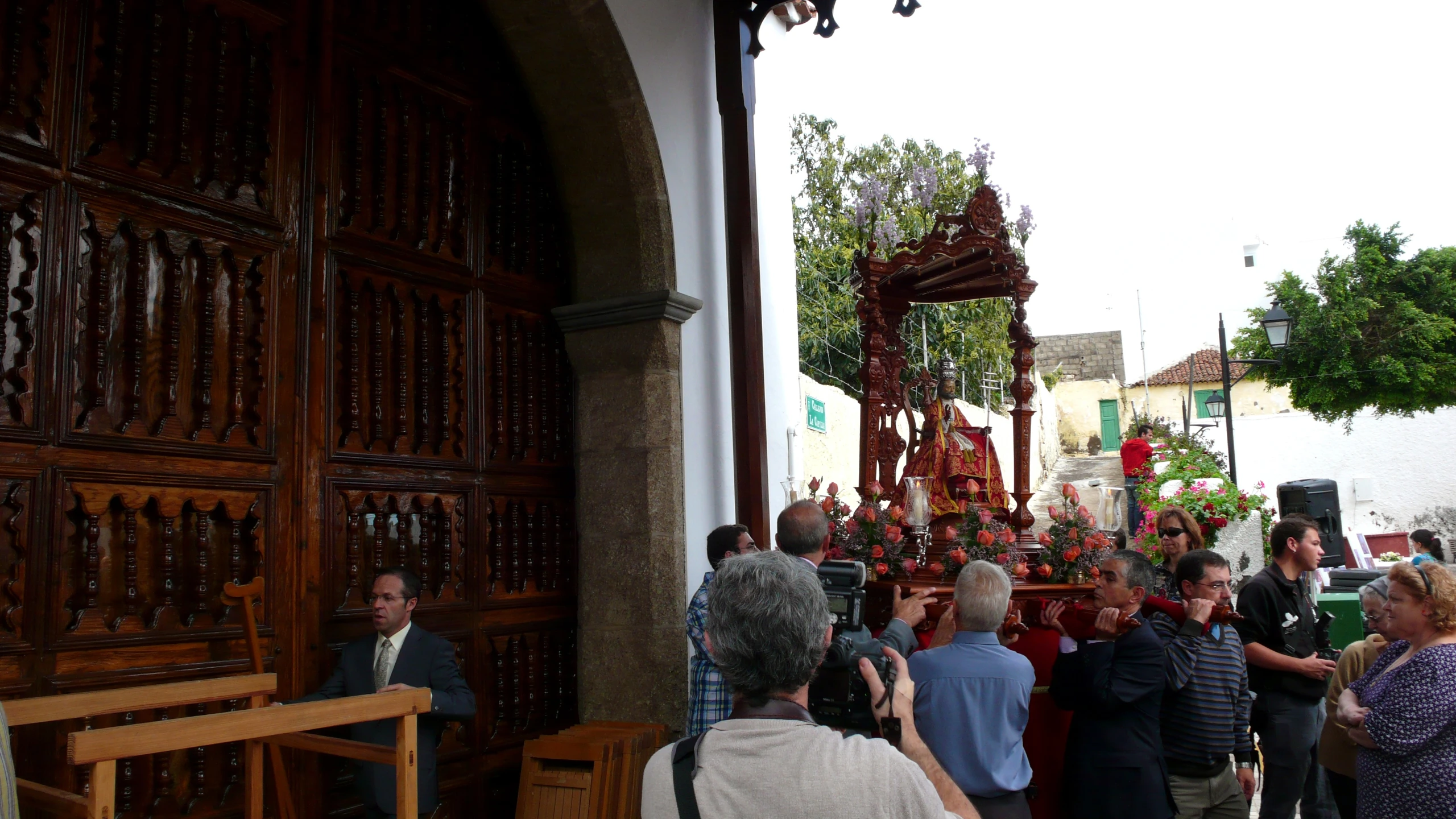 some people gathered around a wooden archway in a town