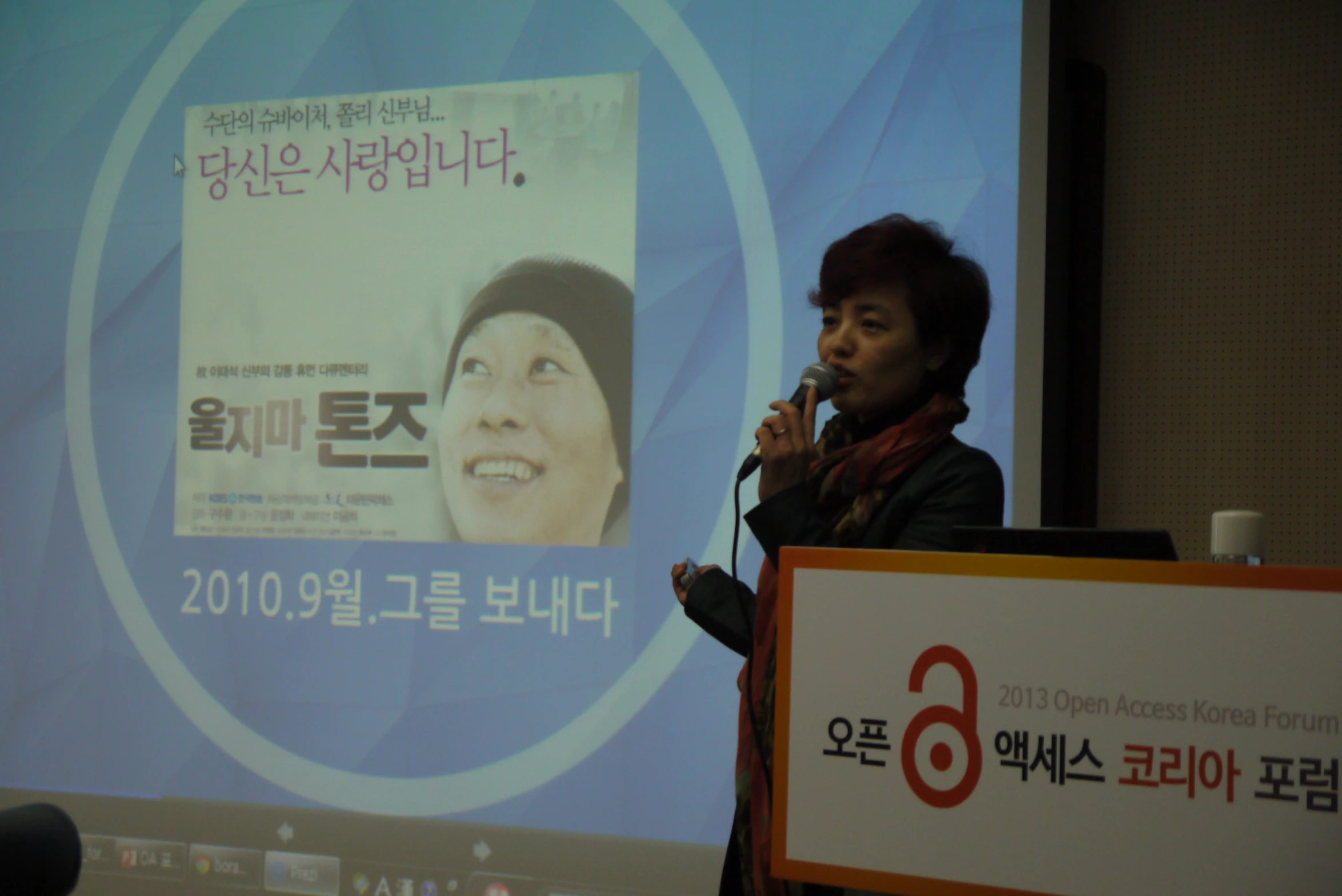 a woman standing behind a podium in front of a projection screen