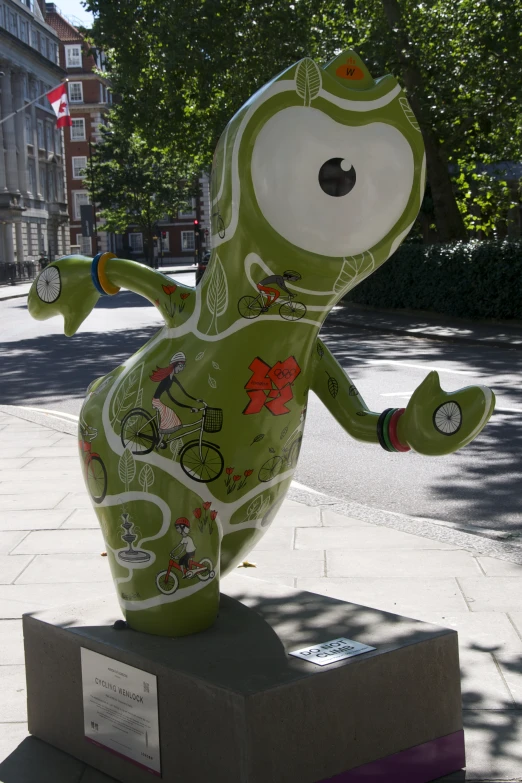 a green lizard statue on a sidewalk in front of a building