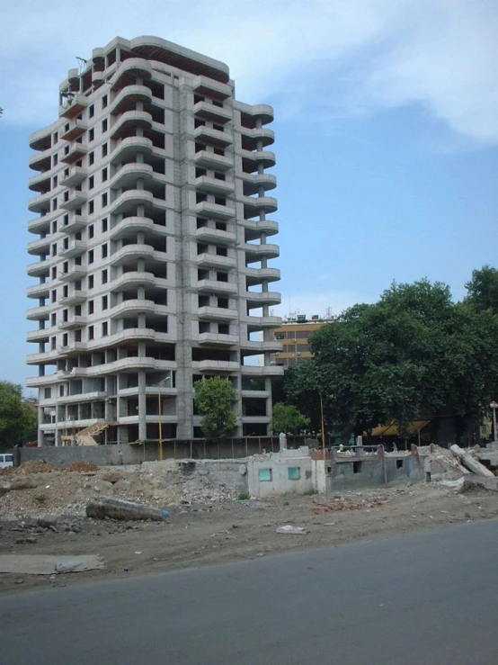 a tall building sitting in the middle of a dirt covered street