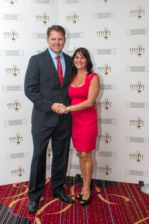 a man and woman posing in front of an awards red carpet